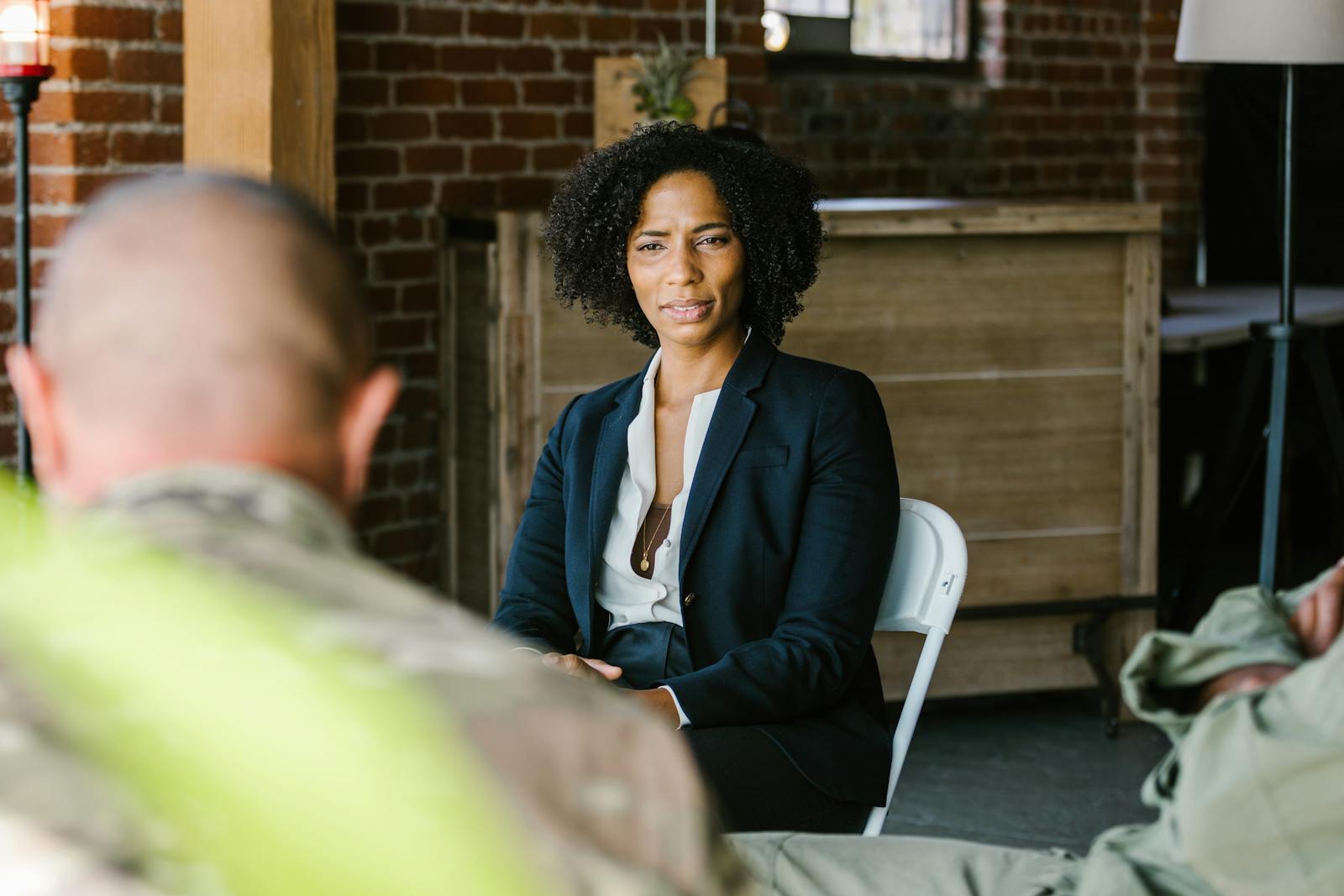 A therapist leads a group therapy session with military veterans in an indoor setting.