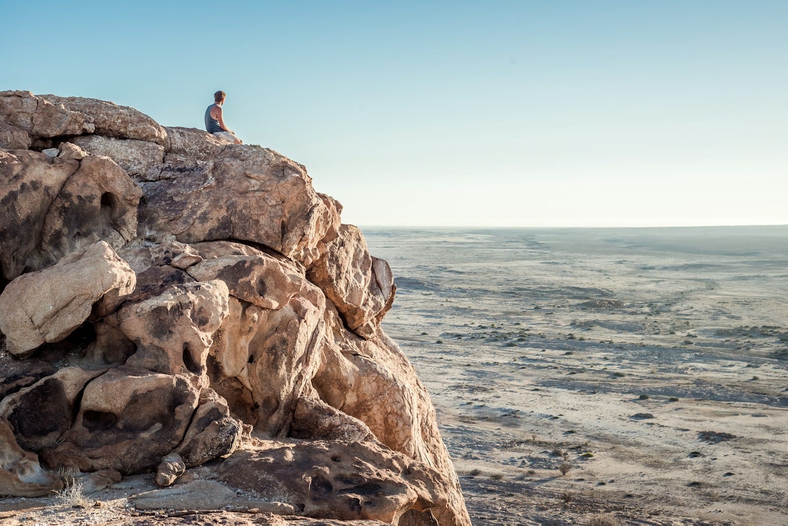 Blog man sitting on top of rock formation near beach