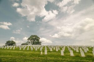 Blog green grass field with white cross under white clouds during daytime