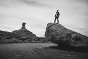 Blog grayscale photo of man standing on rock formation