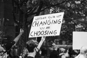 Home grayscale photo of people holding a signage